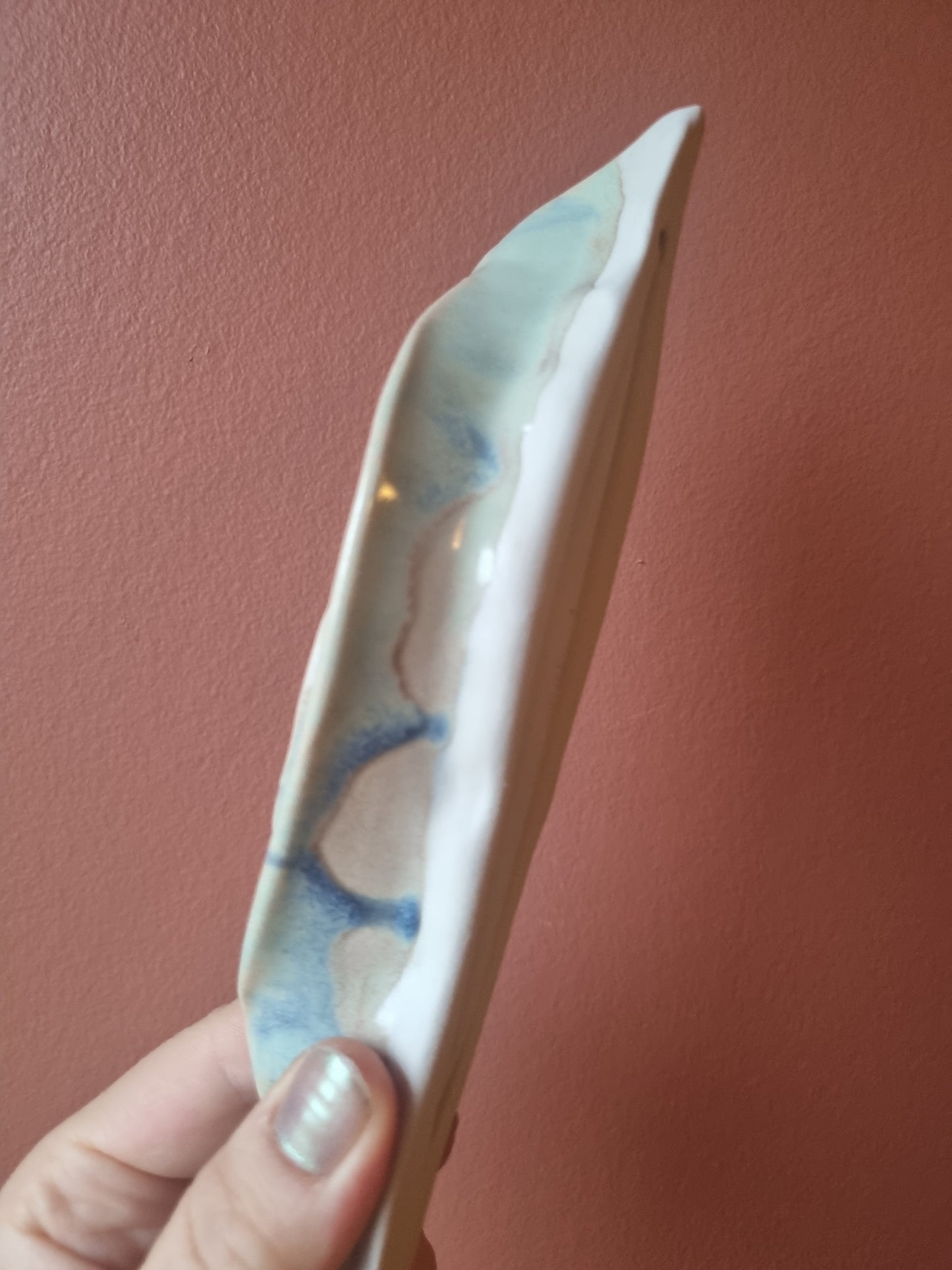 Blå porcelæn keramikkusse set fra siden. Holdt i hånden 